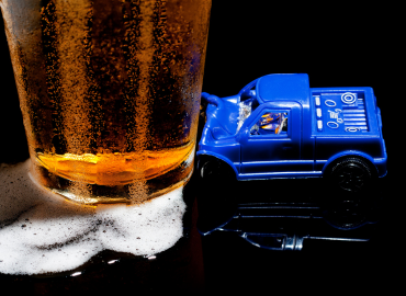 a toy car smashing unto a glass full of beer - a concept of DUI/DWI