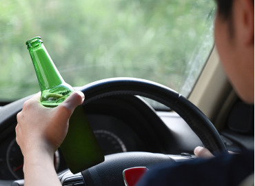 man holding a bottle of beer while driving - DUI